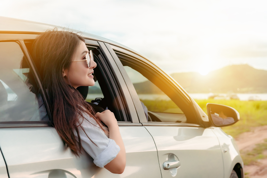 Personal Insurance - Woman with Sunglasses Looking Out Car Passenger Side Window on a Road Trip to a Lake in the Summer